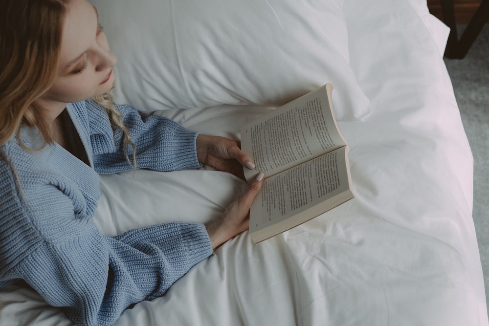 biały komplet pościeli kobieta czyta książkę w łóżku